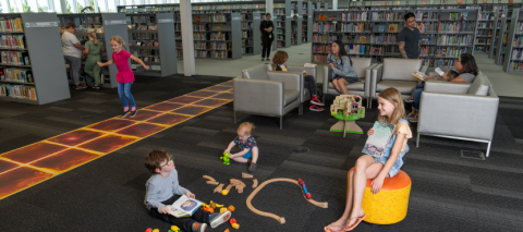 children and families at the library reading books and playing games