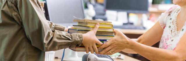 person handing a woman a stack of books